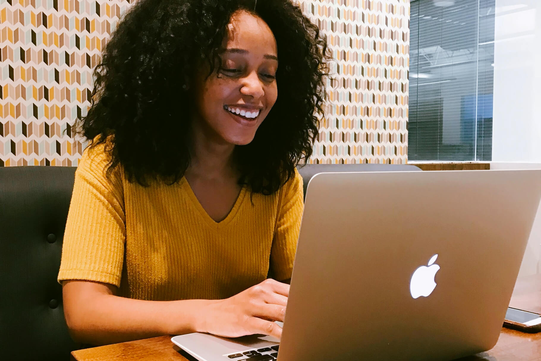 African-american woman in yellow using her laptop